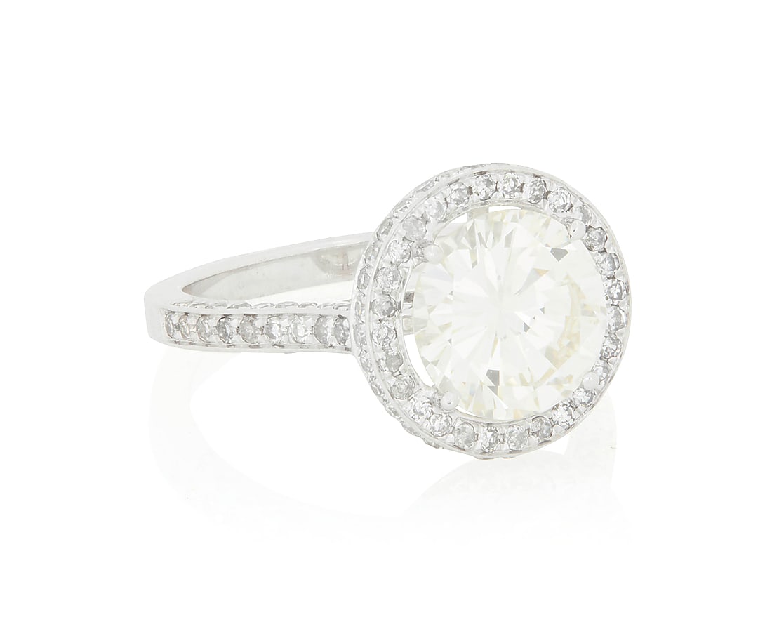 An 18K White Gold and Diamond Ring Centering a round diamond weighing 2.65 carats, accented by: An 18K White Gold and Diamond Ring Centering a round diamond weighing 2.65 carats, accented by single-cut diamonds in a halo design Size: 7 1/2 4.7 grams gross