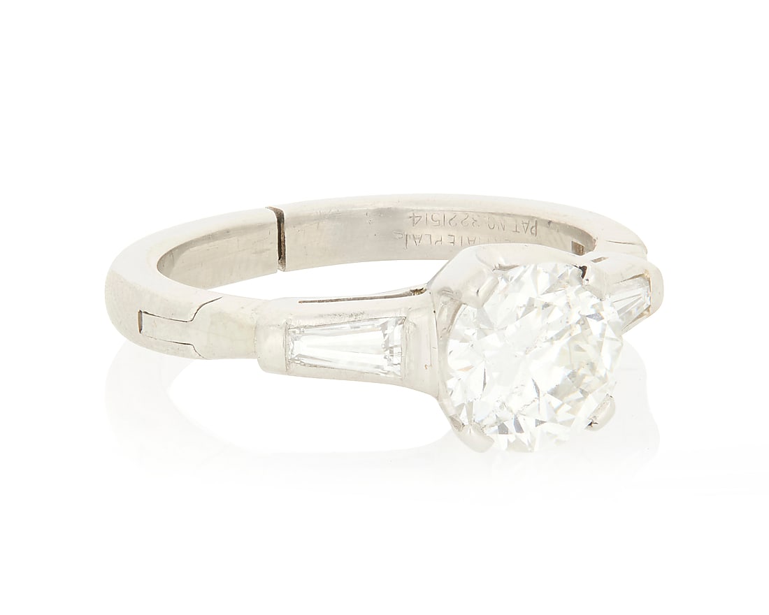 A Platinum and Diamond Ring Centering a round brilliant-cut diamond weighing 1.11 carats, flanked: A Platinum and Diamond Ring Centering a round brilliant-cut diamond weighing 1.11 carats, flanked by two tapered baguette diamonds Size: 4 with a hinged shank 4.9 grams gross Accompanied by a GIA Repo