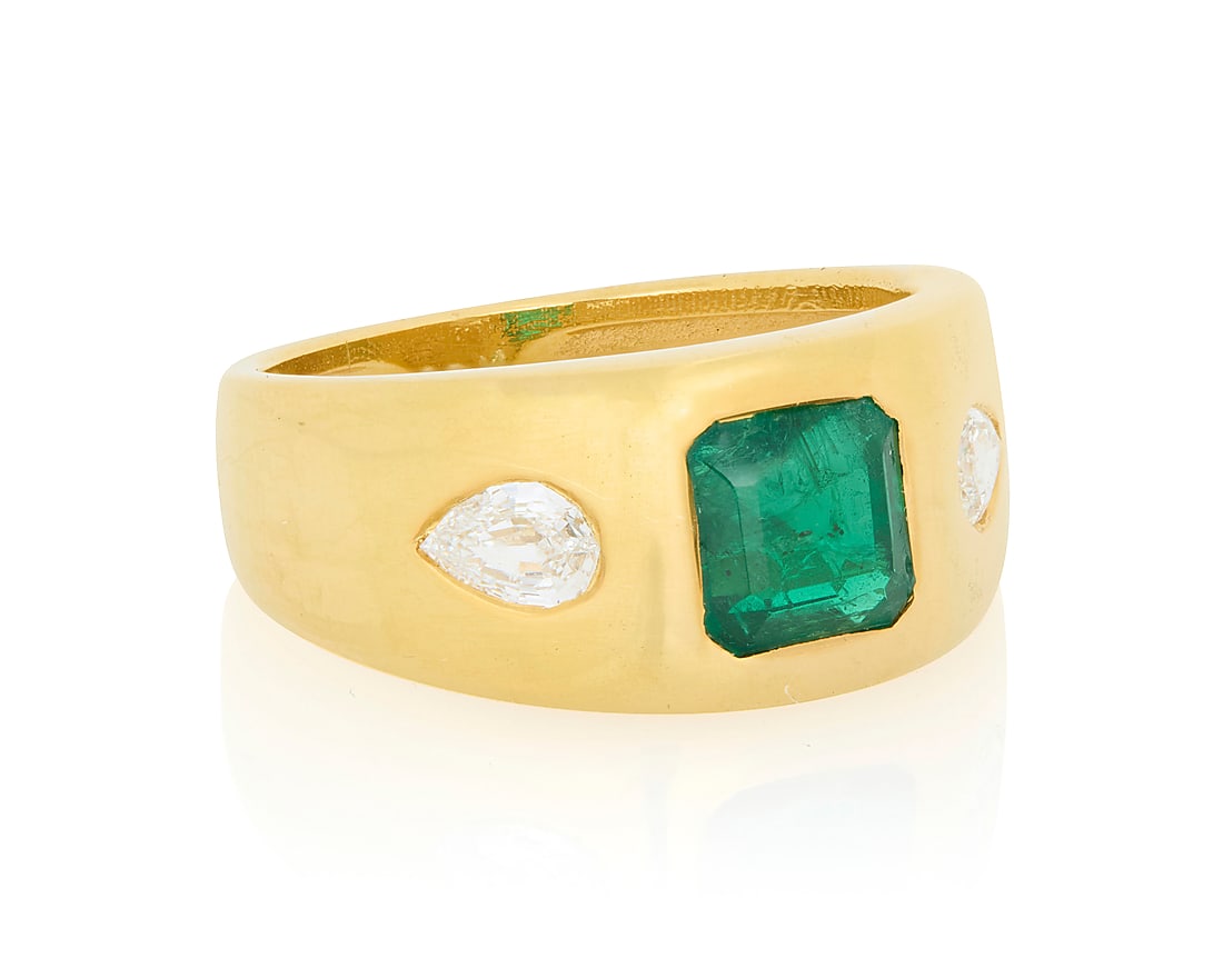 An 18K Gold, Emerald and Diamond Ring Featuring a gypsy set emerald weighing approximately 1.60: An 18K Gold, Emerald and Diamond Ring Featuring a gypsy set emerald weighing approximately 1.60 carats, flanked by two pear-shaped step-cut diamonds Size: 7 7.2 grams gross