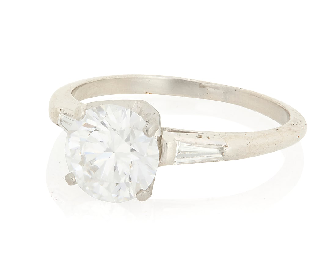 A Platinum and Diamond Ring Centering a round brilliant-cut diamond weighing 1.46 carats, flanked: A Platinum and Diamond Ring Centering a round brilliant-cut diamond weighing 1.46 carats, flanked by two tapered baguettes Size: 6 1/2 4.5 grams gross Accompanied by a GIA Report numbered #5241029231,