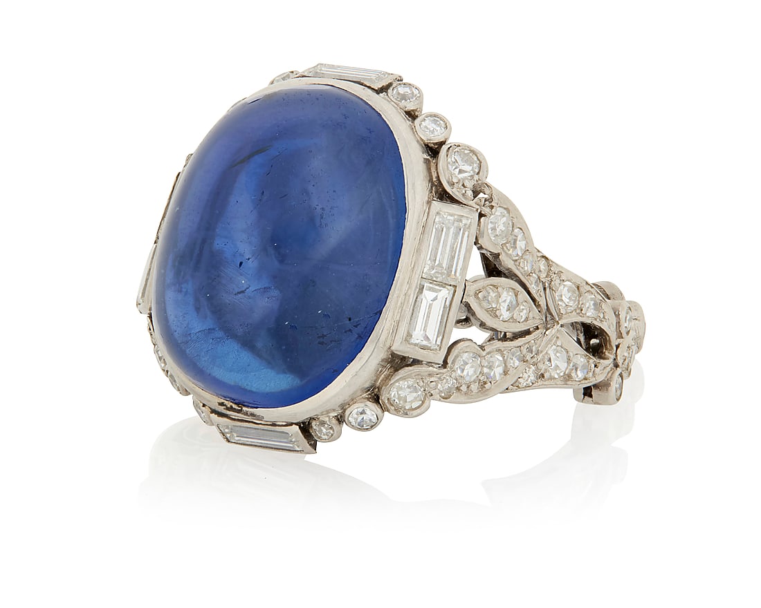 An Art Deco Platinum, Sapphire and Diamond Ring Centering an oval double cabochon weighing: An Art Deco Platinum, Sapphire and Diamond Ring Centering an oval double cabochon weighing approximately 36.80 carats, set in an ornate mount featuring single-cut and baguette diamonds weighing approx
