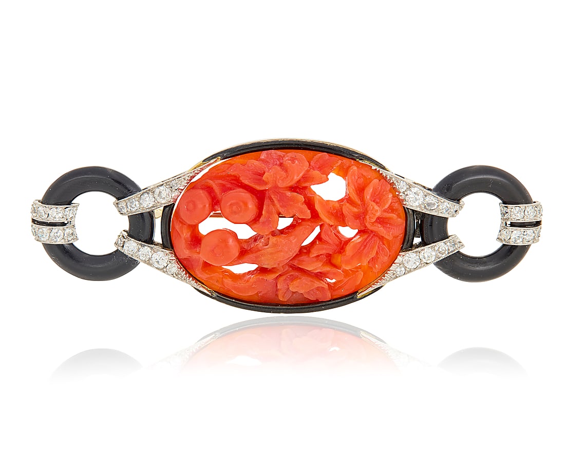 An Art Deco Platinum, Coral and Onyx Brooch Centering a carved red coral featuring fruit, bird and: An Art Deco Platinum, Coral and Onyx Brooch Centering a carved red coral featuring fruit, bird and floral design, accented by round onyx discs finished with single-cut diamonds Measures: 2 3/4 x 1 in.