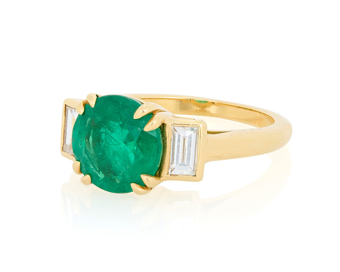 A 18K Gold and Emerald Ring Featuring a round emerald weighing approximately 2.45 carats, accented: A 18K Gold and Emerald Ring Featuring a round emerald weighing approximately 2.45 carats, accented by baguette diamonds weighing 0.45 carat Size: 7 3/4 6.6 grams