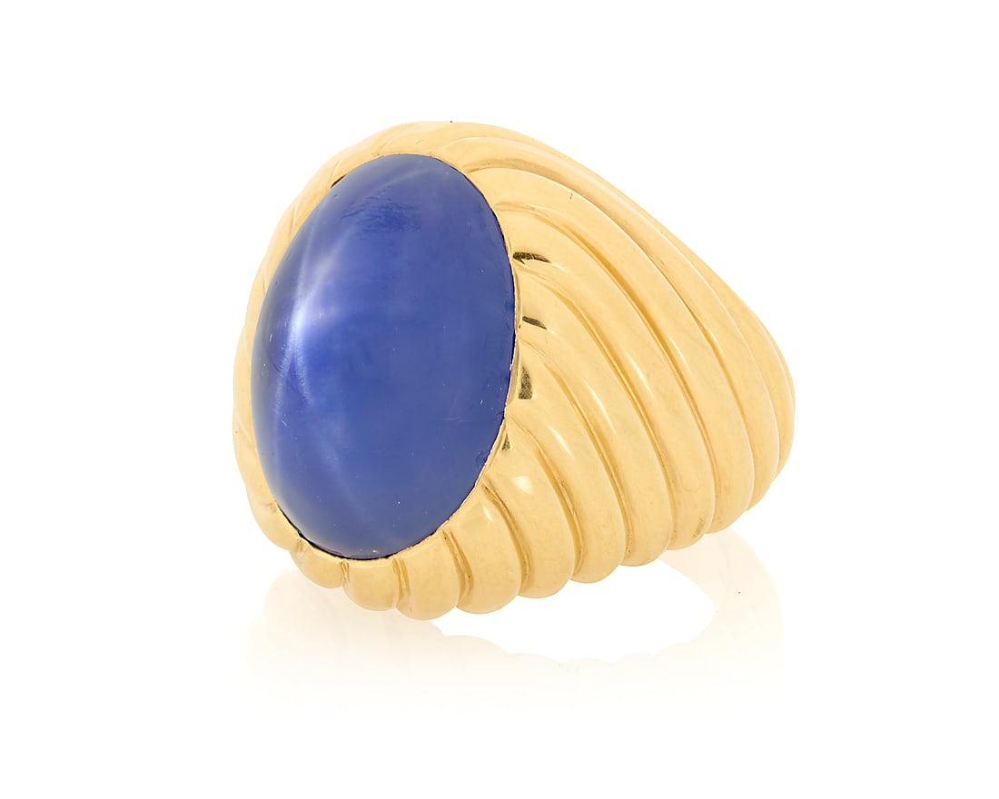 Bulgari: An 18K Gold and Star Sapphire Ring Featuring an oval double cabochon star sapphire: Bulgari: An 18K Gold and Star Sapphire Ring Featuring an oval double cabochon star sapphire weighing approximately 27.23 carats, set in a high polish fluted mounted, signed Bulgari, with Italian works