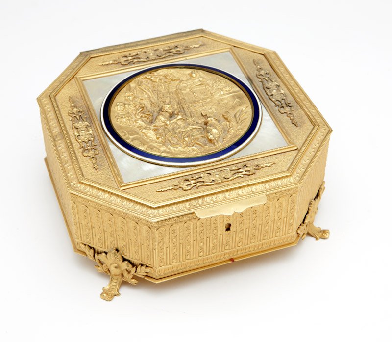 A French gilt bronze casket: Early 20th century, marked ''France'', octagonal, the hinged lid inset with a relief-cast roundel depicting a seated couple in a landscape, within a blue and white enamel border within a mother-of-pea
