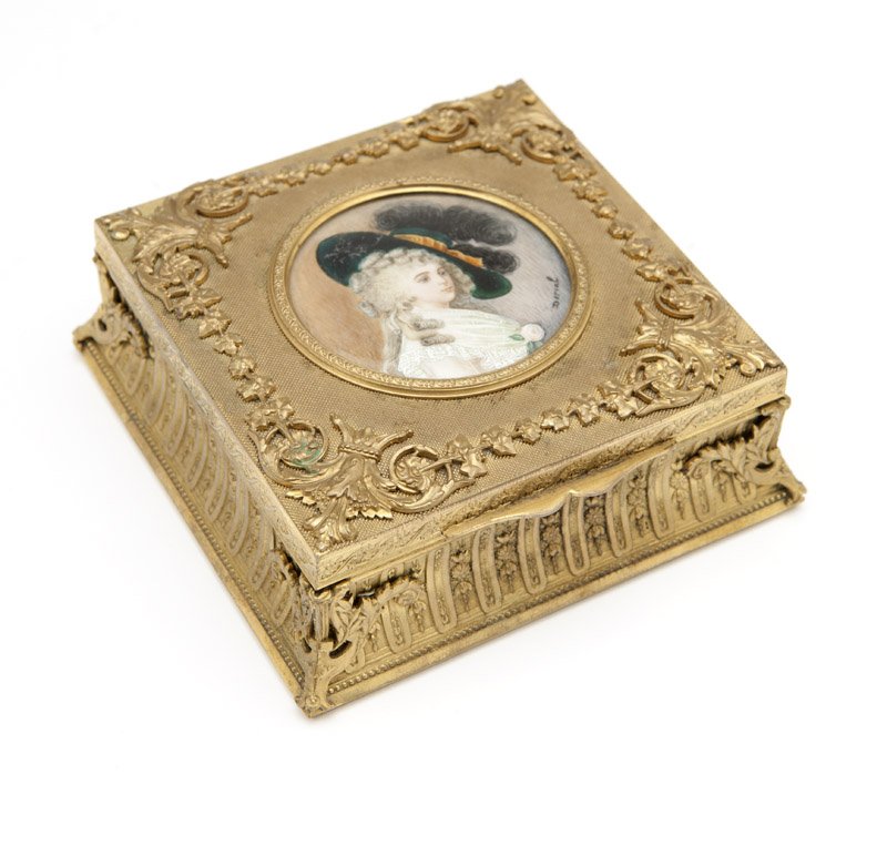 A Continental gilt bronze jewelry box: Late 19th century, with paper label ''I. Bachi / Gioielliere / Via Roma, 5 / Torino'', square, the hinged lid relief-cast with foliate scrolls and garlands and centering a circular inset hand-painted 