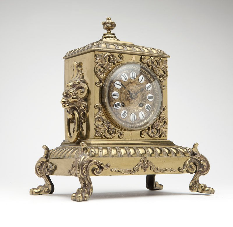 A Tiffany & Co brass mantel clock: Late 19th century, movement stamped ''Tiffany & Compy. / 2763 / 4 / 11'', the circular cast brass dial with oval white enamel cartouches with black enamel Roman numerals, beneath a glazed aperture wit