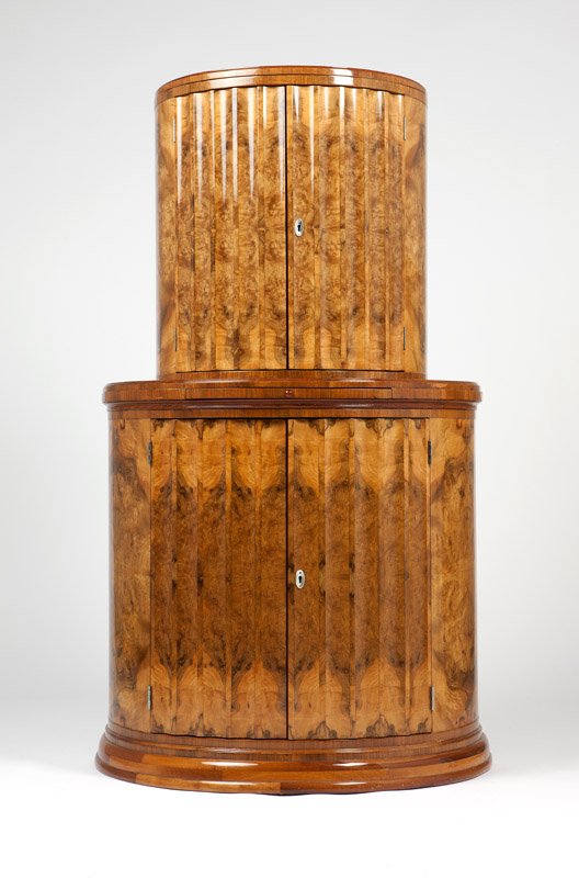 An Art Deco Carpathian elm demilune bar cabinet: Circa 1930, possibly English, the top section with a pair of fluted hinged doors reversing to open shelves and brackets for bar tools, opening to a mirror-backed interior fitted with an open glass she