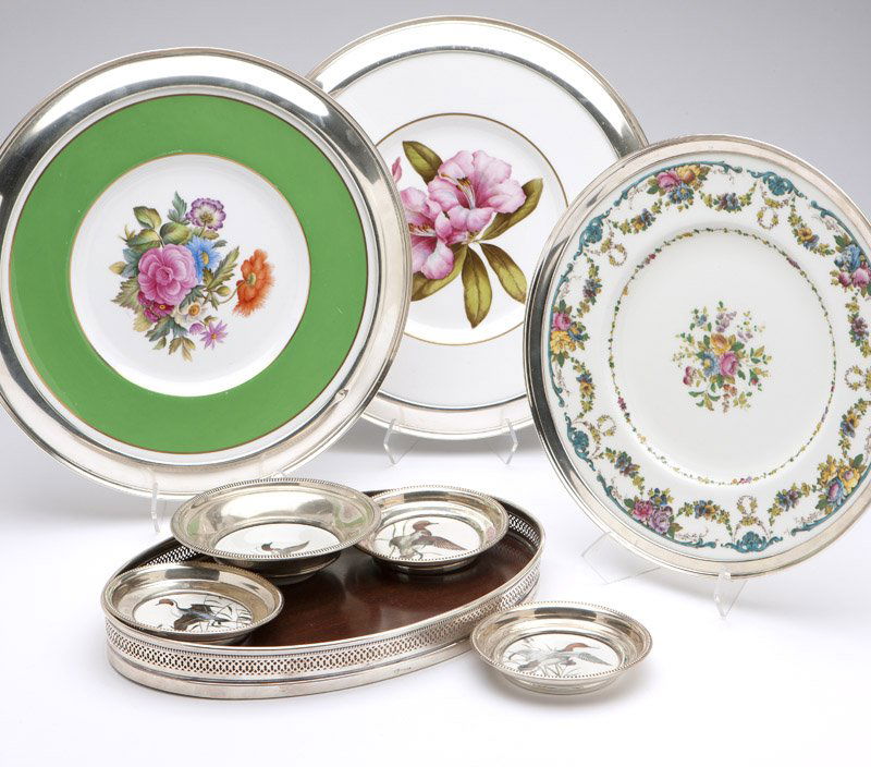 Seven sterling-mounted porcelain dishes & a wooden tray: 20th century, each marked ''Sterling'', comprising: three coasters (4.375'' Dia) and a dish (1.375'' H x 5.5'' Dia.), marked ''Decorated by Delano Studios Setauket, LI, NY / Exclusively For Frank M. W