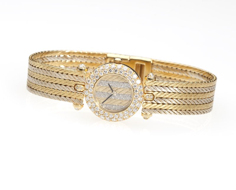 A Van Cleef & Arpels gold & diamond quartz watch: The circular dial attached to a quartz 7 jewel movement signed ''Gerald Genta'' (for Van Cleef & Arpels); within an 18K yellow gold case, the bezel and lugs set with 76 full-cut diamonds totaling appr