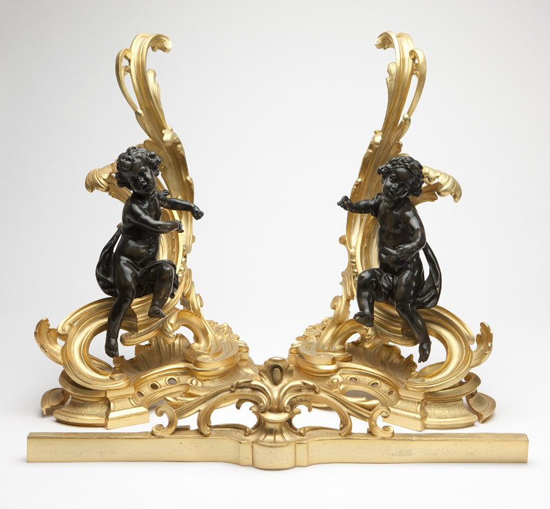 A pair of Rococo style gilt & patinated bronze chenets: Late 19th / 20th century, each with a cherub perched on a rocaille, scroll and foliate-cast base, together with fender, 3 pcs, each 21.5'' H x 15.5'' W x 8'' D, est: $2500/3500 Provenance: Property of