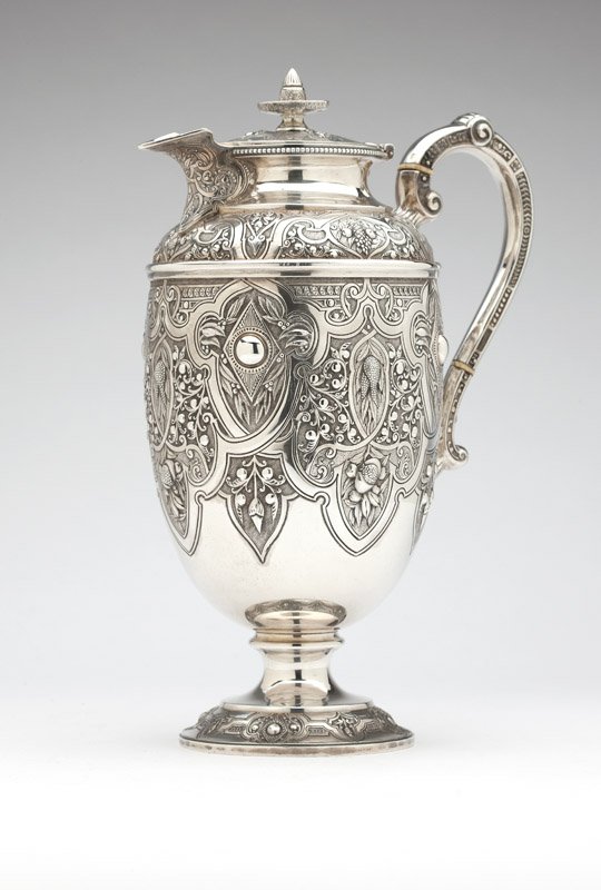 A Victorian sterling silver ewer: 1873, Glasgow, maker's mark ''GE & (?)'' (probably George Edward and Sons), the hinged lid over an ovoid body issuing a scrolled handle and short spout, chased and repousse-decorated all over in Renai