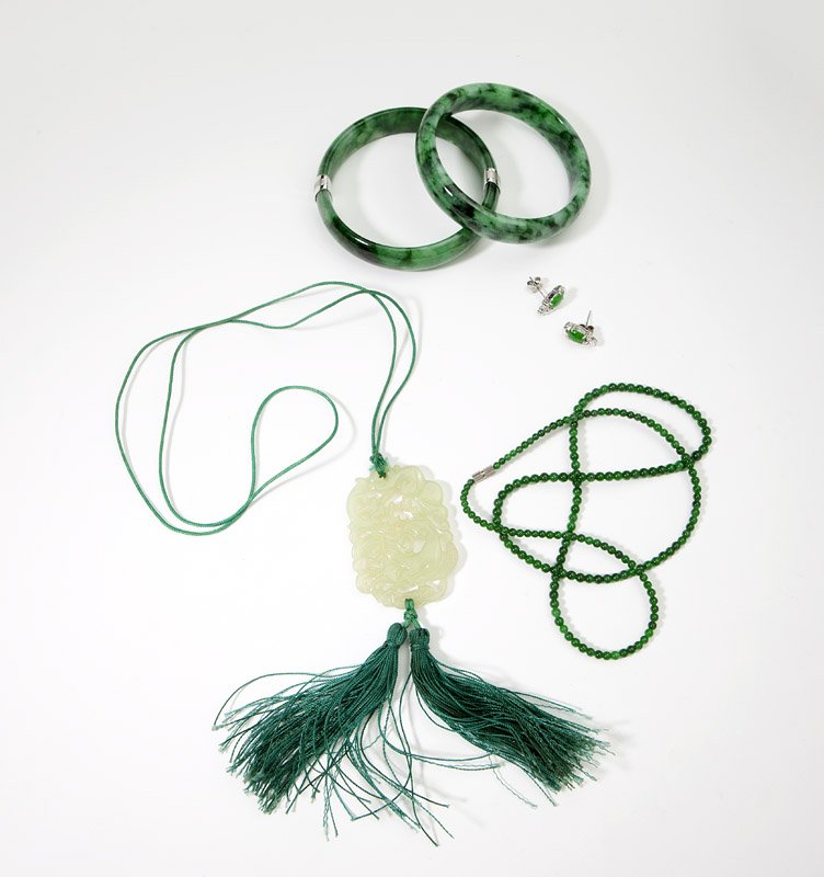 A collection of hardstone and jade jewelry: Featuring two bangles, a beaded necklace, a pair of jade and white gold earrings and a carved serpentine pendant on a cord, 6 pcs, est: $800/1200