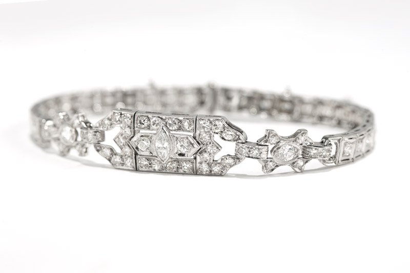 An Art Deco diamond and platinum bracelet: Circa 1920, platinum with center sectional set with one marquise and connector sectionals and remaining line strap, set with 70 single and full-cut diamonds totaling approximately 1.95 cts, graded H-I