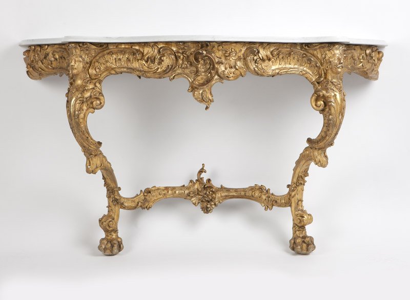 A Rococo style carved giltwood console table: Late 19th century, likely Italian, of gilt carved and gessoed wood construction with pine secondary wood, the serpentine beveled-edge white marble top over a foliate-scrolled and rocaille apron raised