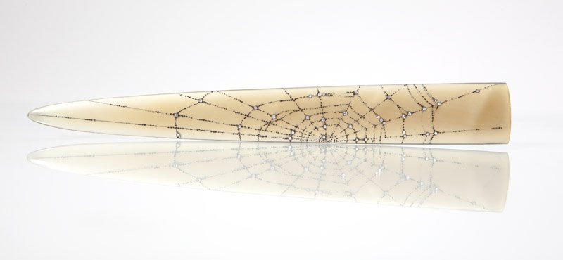 A carved horn & diamond paperknife, Martin Baker: Signed MB for Martin Baker, buffalo horn engraved in a spiderweb motif accented with 68 full-cut diamonds bezel set in silver totaling approximately 0.35 ct, 7 5/8'', est: $500/800