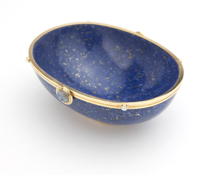 A small lapis and gold frame bowl, Silverhorn: Stamped for Silverhorn, 18K gold frame and footed base on small oval lapis lazuli bowl trimmed with two carved ''Man in the moon'' labradorites and four seed pearls, 4 1/8''L x 3''W x 1 5/8H, est: $10