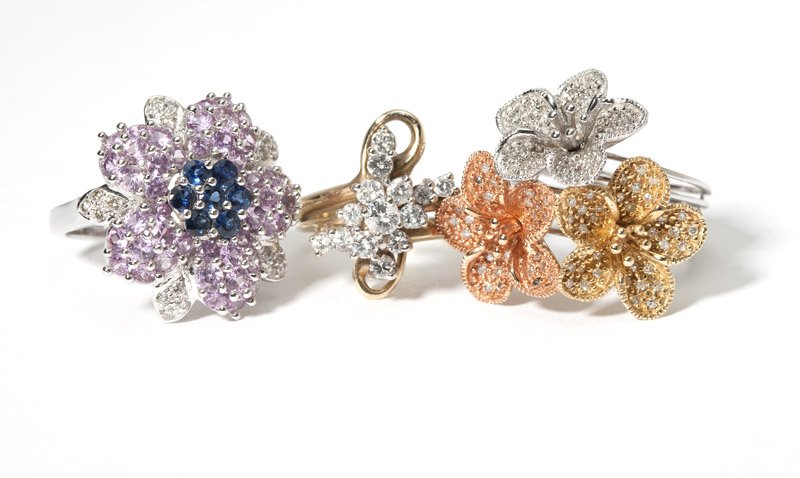 A collection of three diamond, gem and gold rings: A 14K gold and full-cut diamond cluster ring size 5 1/4, one 14K white gold ring with tri-color gold flowers set with single-cut diamonds, size 8, together with a 14K white gold flower set with pink a