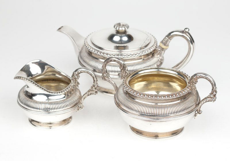 A George III sterling silver tea set: 1820, London, each with maker's mark for Benjamin Smith III, a three-piece set, each with a gadrooned rim and shoulders, the sugar bowl and milk jug each engraved with a swan armorial to one side, com