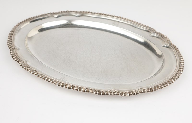 A George III sterling silver serving platter: 1806, London, with maker's mark ''NH'' within a rectangle for Henry Nutting or Hannah Northcote, the shaped oval gadrooned-edge rim with dual engraved armorial shields, 1'' H x 17.875'' W x 13.5'' D, 