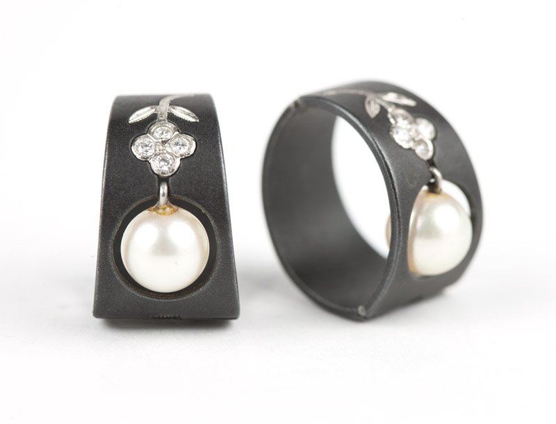 A pair of cultured pearl earclips, Marsh & Co.: Circa 1950, a pair of blackened steel earclips with a circular opening for cultured pearl to drop, with a full-cut diamond and white gold flower above, unmarked for Marsh and Co., est: $800/1200