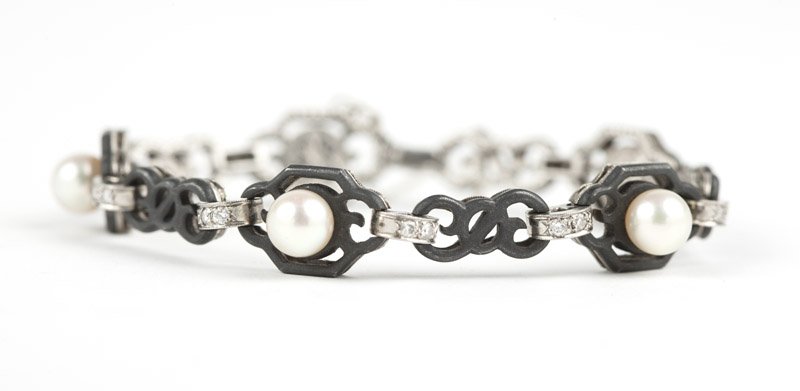 A cultured pearl and steel bracelet, Marsh & Co.: Circa 1950, a pierced blackened steel sectional bracelet atop an 18K white gold frame centering a cultured pearl with full-cut diamond connectors, unmarked for Marsh & Co., 7 1/8'', est: $2000/3000