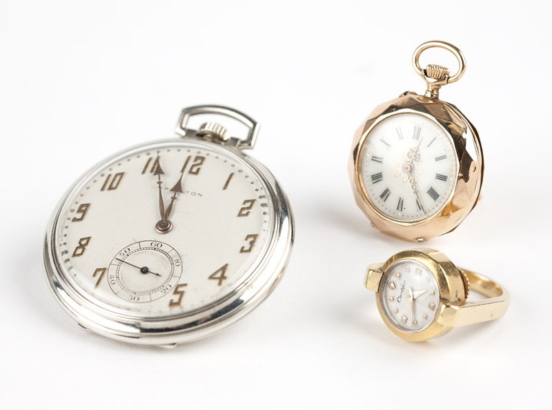 A group of three gold timepieces: The first: a Hamilton 14K white gold pocket watch with circular white dial, applied gold-tone Arabic numerals, sub-seconds, signed ''Hamilton'', attached to a 23 jewel manual stem wind and set movemen