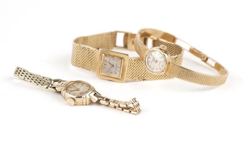 Group of three lady's gold wristwatches: The first: a lady's Patek Philippe 18K yellow gold wristwatch, with circular silvered dial with gold-tone baton hour markers, signed ''Patek Philippe Geneve Howes'', attached to a 20 jewel manual wind