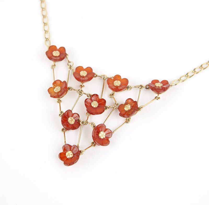 A gold and floral carved carnelian bib necklace: An 18K gold chain attached to a triangular bib with floral carved carnelian, 15 1/2'', 13.2 gms gross, est: $200/400 Provenance: Property from a Pasadena Collector