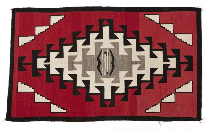A Navajo Southwest regional pictorial rug: Mid-20th century, red field with central bow and arrow motif, with gray, black and cream designs, 5'10'' H x 3'6'' W, est: $800/1200 Provenance: Private Collection, Roswell, NM