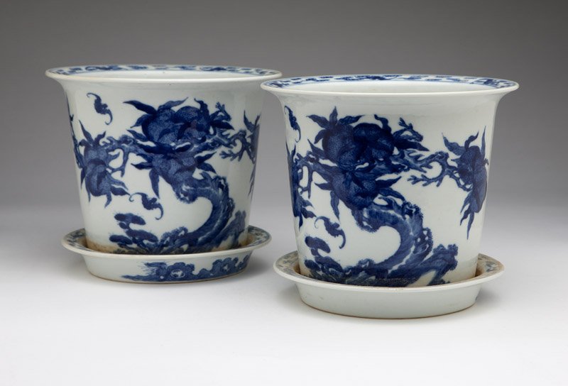 Pair of Chinese blue and white porcelain jardinieres: Late Qing Dynasty, circa 1890, each with a slightly flaring circular rim hand-painted with bats and stylized clouds surmounting a circular tapering body decorated with a fruiting peach tree and bats i