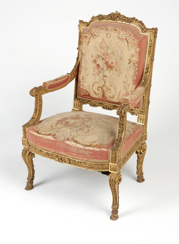 A Louis XV-style giltwood fauteuil: Late 19th century, the ribbon-molded giltwood crestrail relief-decorated with roses, over a squared Aubusson tapestry-upholstered back, connected to the conforming seat by padded rose-adorned scrolled