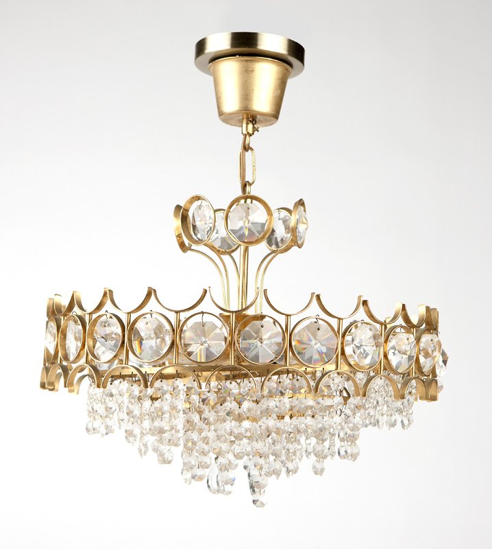 A brass and crystal chandelier, Massimo Scolari: Circa 1970s, a polished brass and cut-crystal chandelier, surmounted by six bezel-hung octagonal crystals, with an arrangement of six lights above hanging concentric rings each issuing lengths of crys