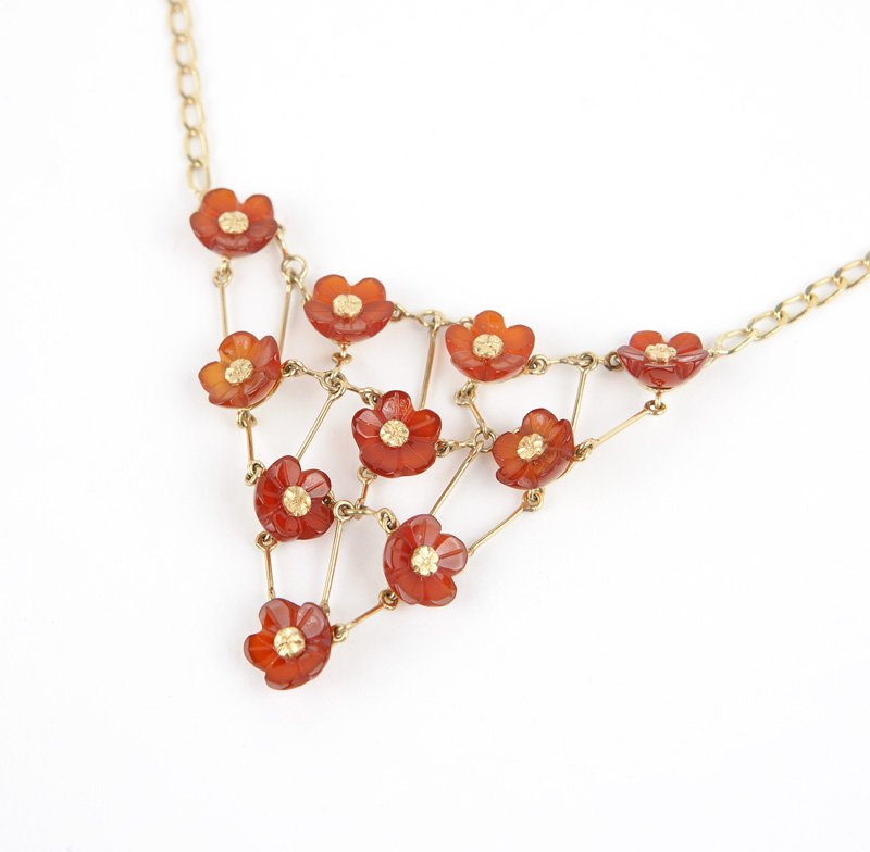 A gold and floral carved carnelian bib necklace: An 18K gold chain attached to a triangular bib with floral carved carnelian, 15 1/2'', 13.2 gms gross, est: $200/400 Provenance: Property from a Pasadena Collector