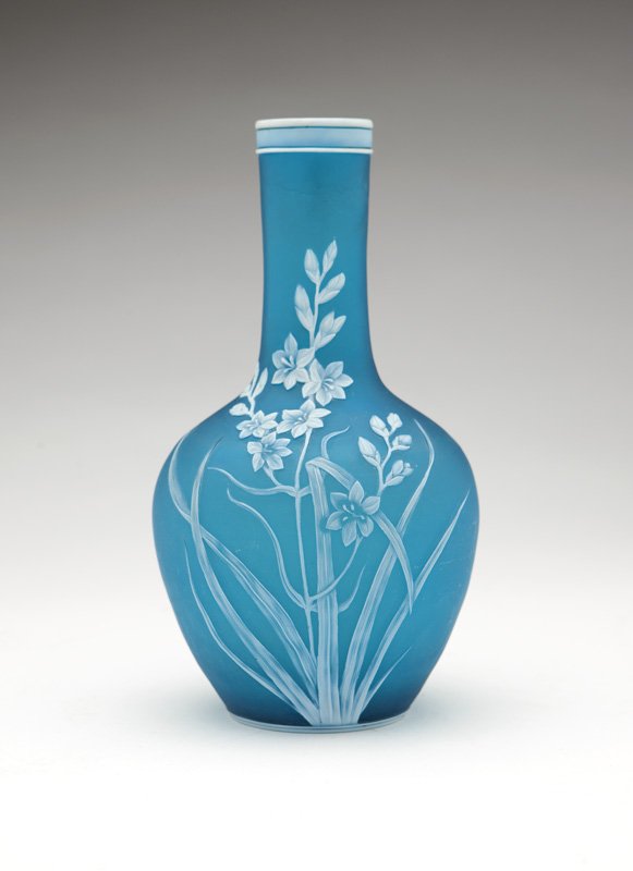 A Thomas Webb & Sons cameo glass vase: Late 19th century, maker's mark to underside, of white opaque cut back to turquoise glass, the tall cylindrical neck over an ovoid body, decorated with a blooming flower and butterfly motif, 9'' H x 4