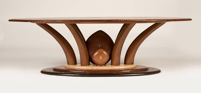 Steven Spiro (20th century- Madison, WI): Circa 2005, apparently unsigned, a hand-carved and inlaid cocktail table, with an oblong top inlaid with a fossil, a mother-of-pearl button and various woods in abstract motifs, raised on rounded outs