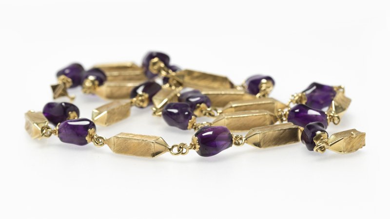 An amethyst bead and gold sectional necklace: A 14K yellow gold tapered textured rectangular-shaped sectionals alternating with free-form amethyst beads, length 26 1/2'', 42.8 gms gross, est: $800/1200