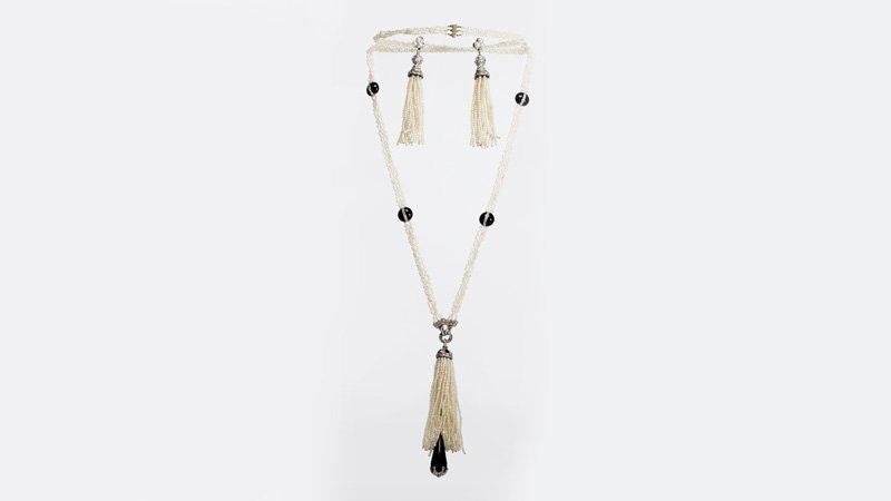 A seed pearl & onyx tassel necklace and earrings: Circa 1910, a long woven seed pearl necklace with onyx bead sectionals set with rose-cut diamonds in platinum, with a diamond and platinum connector to a seed pearl tassel set with a diamond and onyx