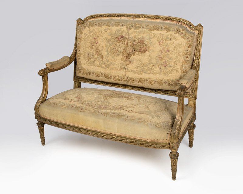 A Louis XVI-style carved giltwood settee: Second half 19th century, the curved back elaborately carved with rope molding and intertwined floral and foliate garlands, issuing conforming arms above an outcurved padded seat, the seat, back and a