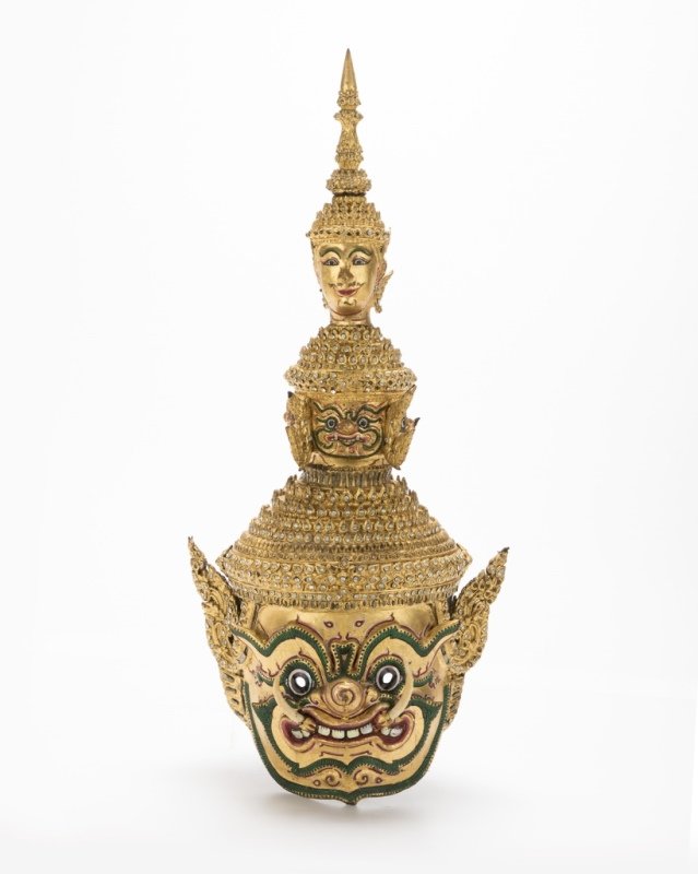 A Thai paper mache mask of Tosakan: Late 19th/early 20th century, Bangkok-style, created for a Khon dance drama, gilt finish with polychrome highlights, adorned throughout with clear gemstones and mirror panels, with bone tusks, with a