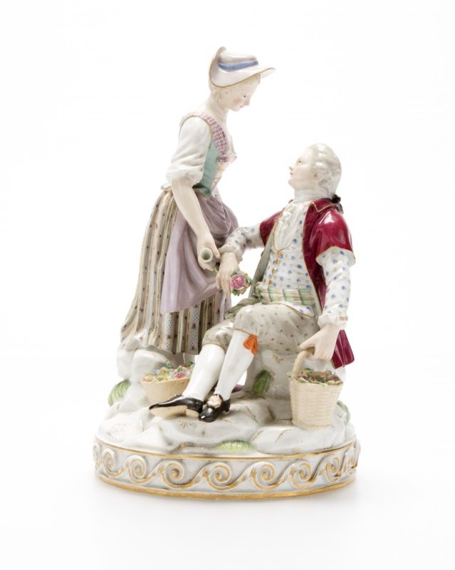 A Meissen porcelain figural group: Late 19th/early 20th century, with blue underglaze crossed swords mark, incised model number ''D87'', depicting a standing lady holding a jug of wine and a seated gentleman, 7.875'' H x 5.25'' W x 4.8