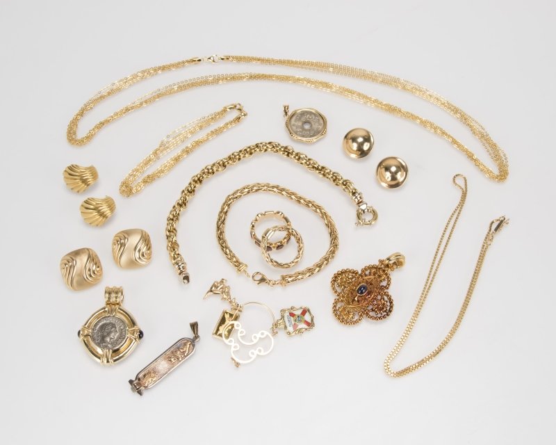 A group of 14K yellow gold jewelry: Including two chain necklaces, three chain bracelets, three pairs of ear clips, a band, three charms on an loop, and a pendant set with a cabochon sapphire, 69.2 grams, together with three white metal