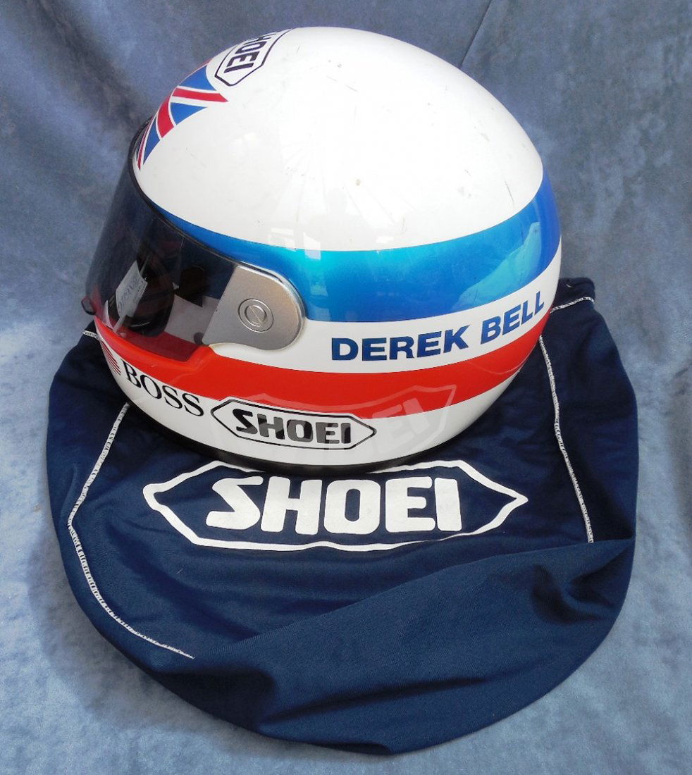 Derek Bell Used Race Crash Helmet: An original Derek Bell SHOEI race helmet in White with applied blue and red stripes and a Union Jack. Driver's name, Boss and Sunrider advertising logos are present. Complete with visor and in excelle