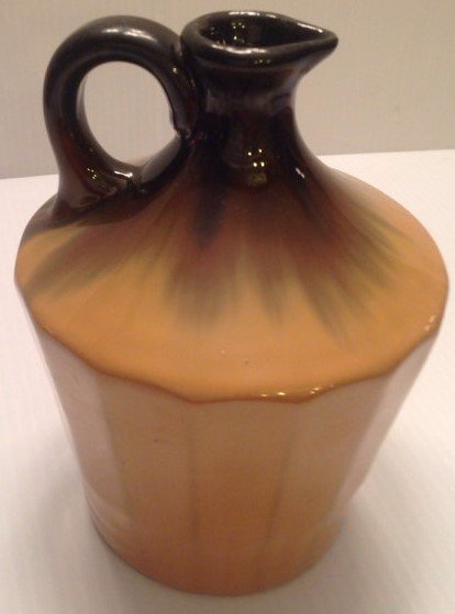 Fulper pottery Jug: This is a early 20th c. Fulper Jug. It measures approx. 8" tall. Diameter on base is approx. 4". The color near the top is brown into a green. The bottom is somewhat tan/peach color with green along r