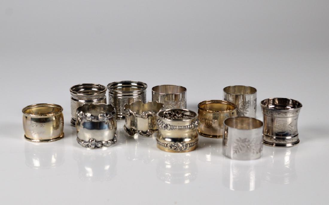 LOT OF ELEVEN SILVER PLATE NAPKIN RINGS: Each with a different pattern and design.