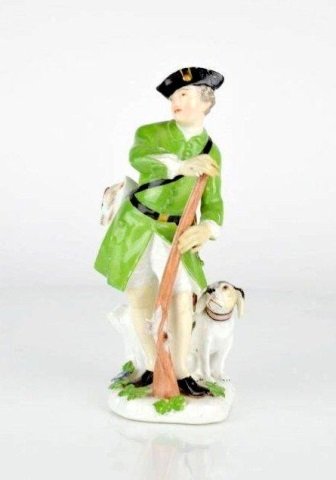 MEISSEN PORCELAIN HUNTER FIGURE: Wearing green coat with rifle in hand and dog at his feet. Unmarked. Repair to right hand and hat. Loss of fingertip to right hand. British Antique Dealers' Association label at base. H: 7 1/8 in. (18