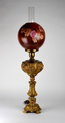 19TH CENTURY BANQUET LAMP: With hand painted globe and ornate cast work featuring women's faces and rams heads. Electrified. Ht. to top of chimney 84 cm. (33 in.)