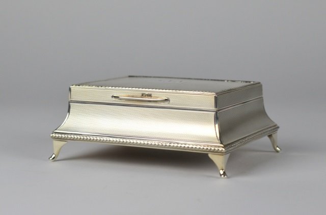 ENGLISH SILVER FOOTED CIGARETTE BOX: Cedar lined sarcophagus body with turned engine design. Good condition.