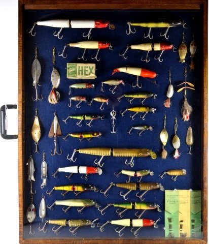 COLLECTION OF VINTAGE FISHING LURES: Mostly wooden lures in a large display case including Creek Chub, Hex, Lucky Strike, Old Wooden Bait Co., A.W.S., Pflueger, C. C. Roberts, & others.