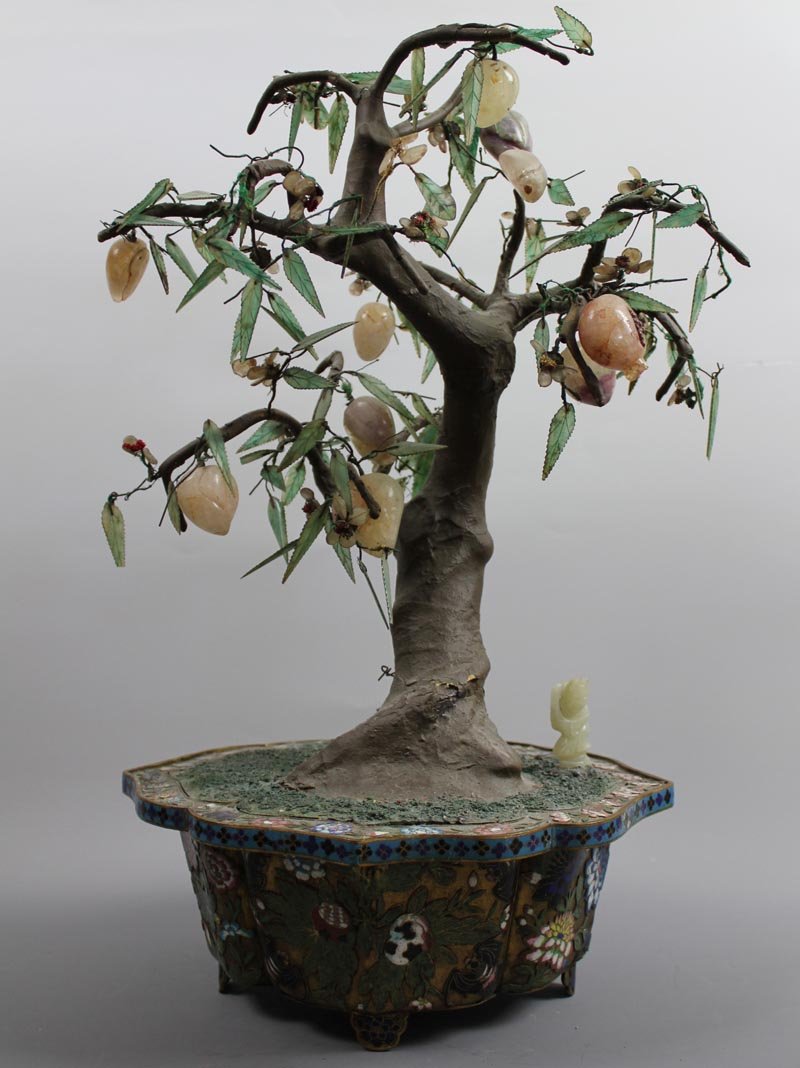 A large Chinese jade tree in a cloisonné: A large Chinese jade tree in a cloisonné jardinière various blossoms and leaves in rock crystal, quartz, and other hardstone details with knotted string accents, one white jade boy under the